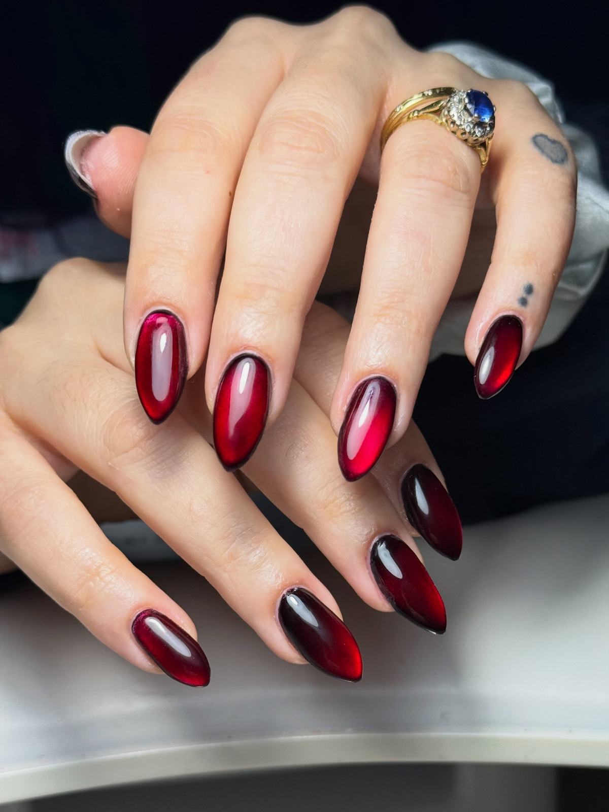 Glossy deep-red jelly almond nails fading darker at the tips