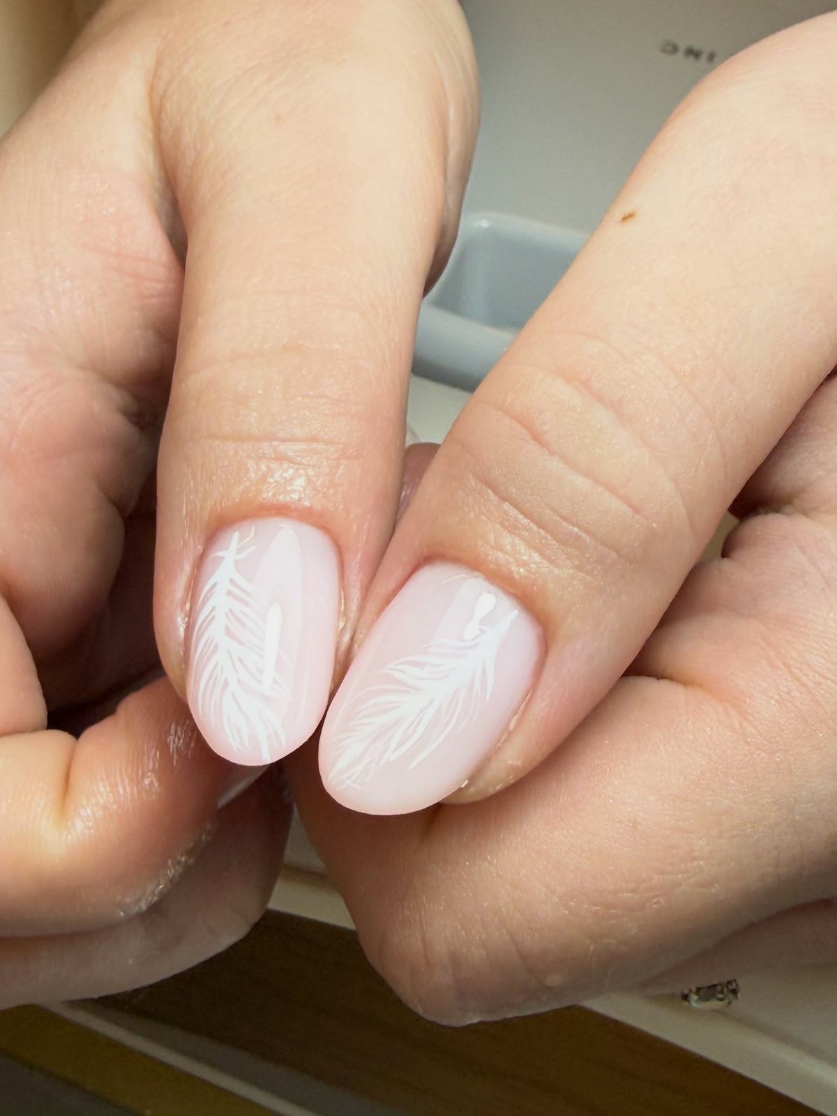 Milky-pink almond nails with white feather art